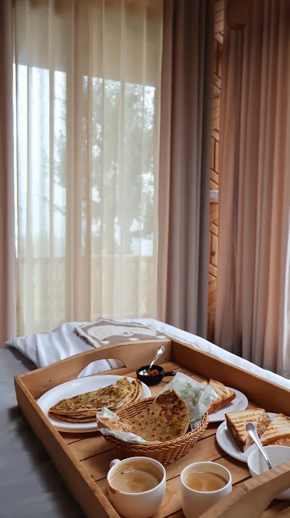 Tray of parathas, toasted sandwiches and tea beside sheer curtains