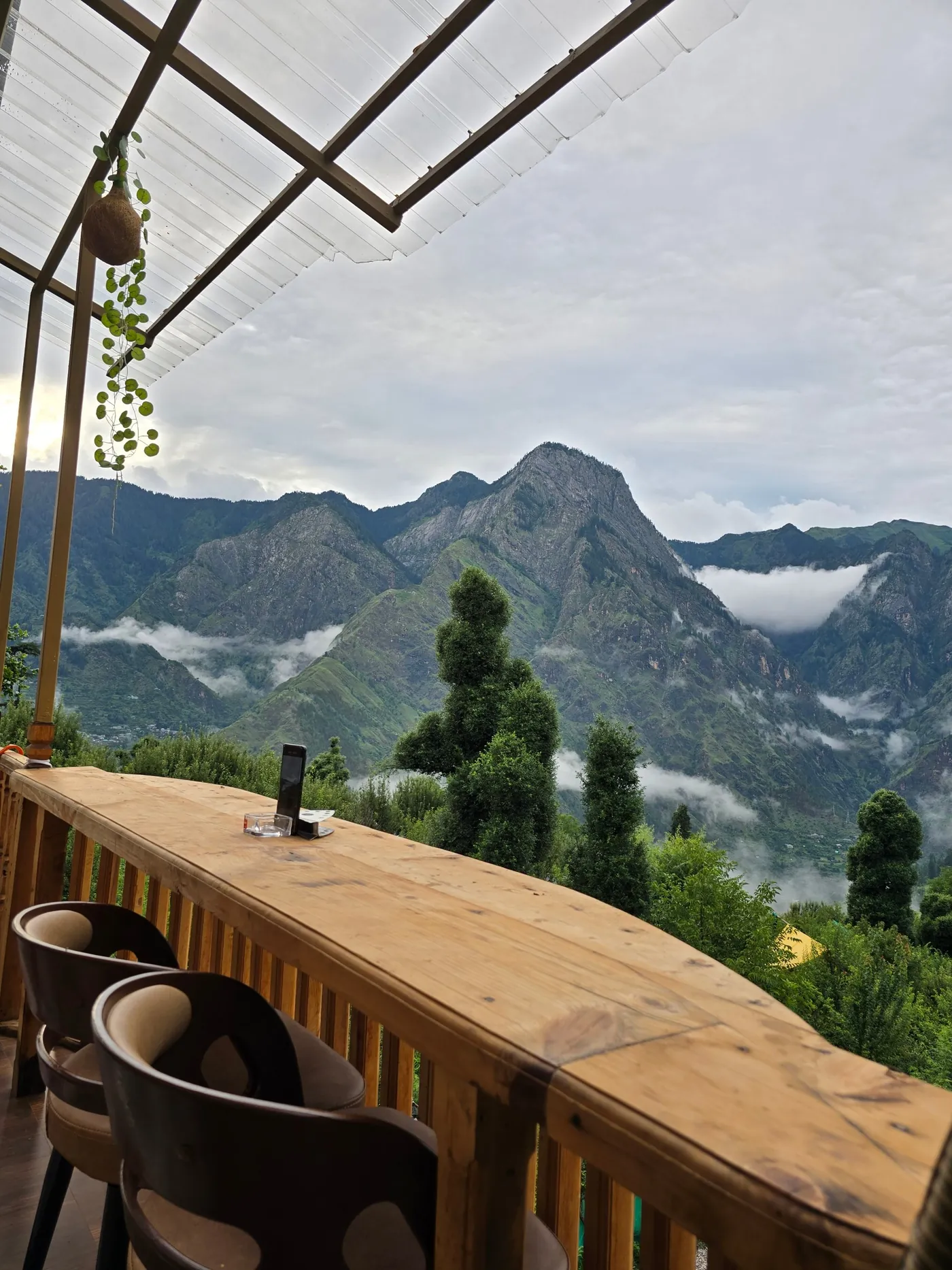 Cloud-wrapped Himalayan peak above green trees seen from the deck