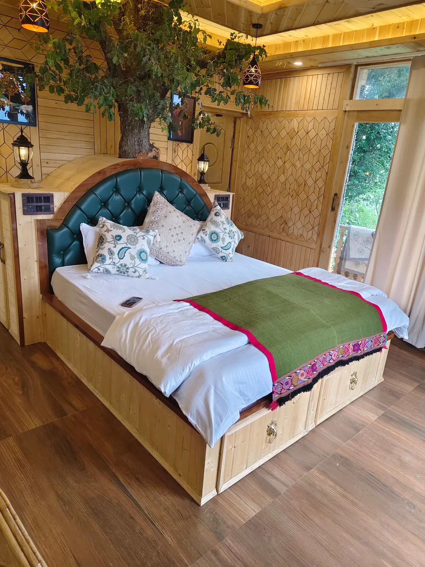 King bed in white linen with a green Himachali throw and floral cushions