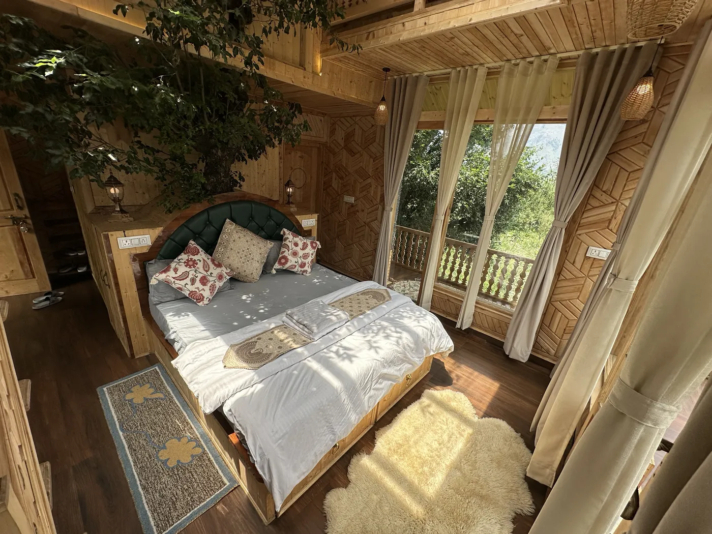 View down onto the king bed in the Duplex Tree House, with sunlit windows and the orchard outside