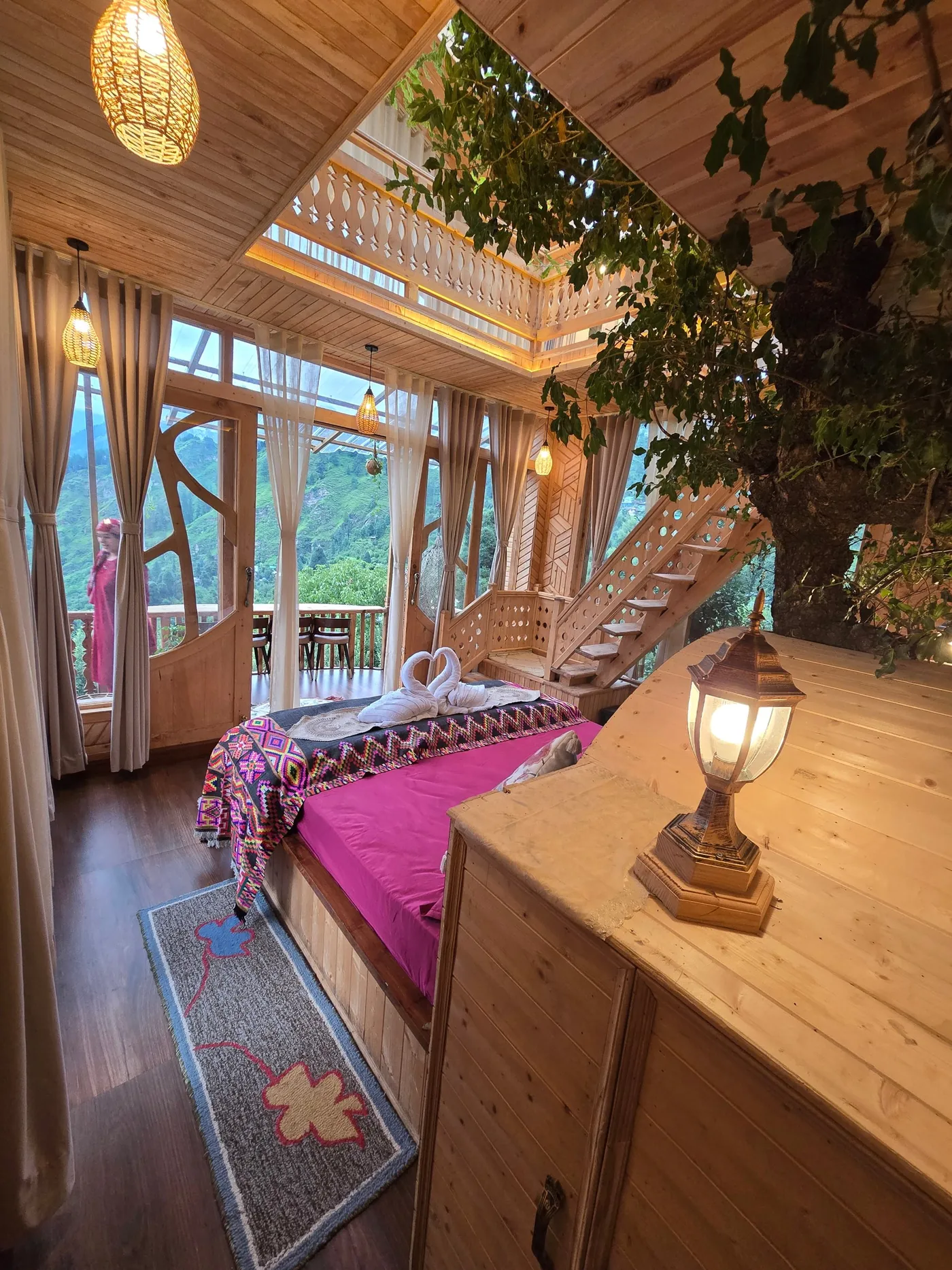 Duplex bed with a Himachali runner, a lantern and the staircase beyond