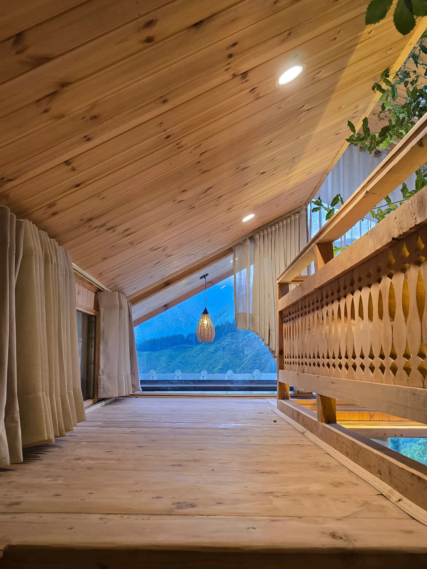 Upper level passage of the Duplex Tree House with a carved timber balustrade and a mountain view